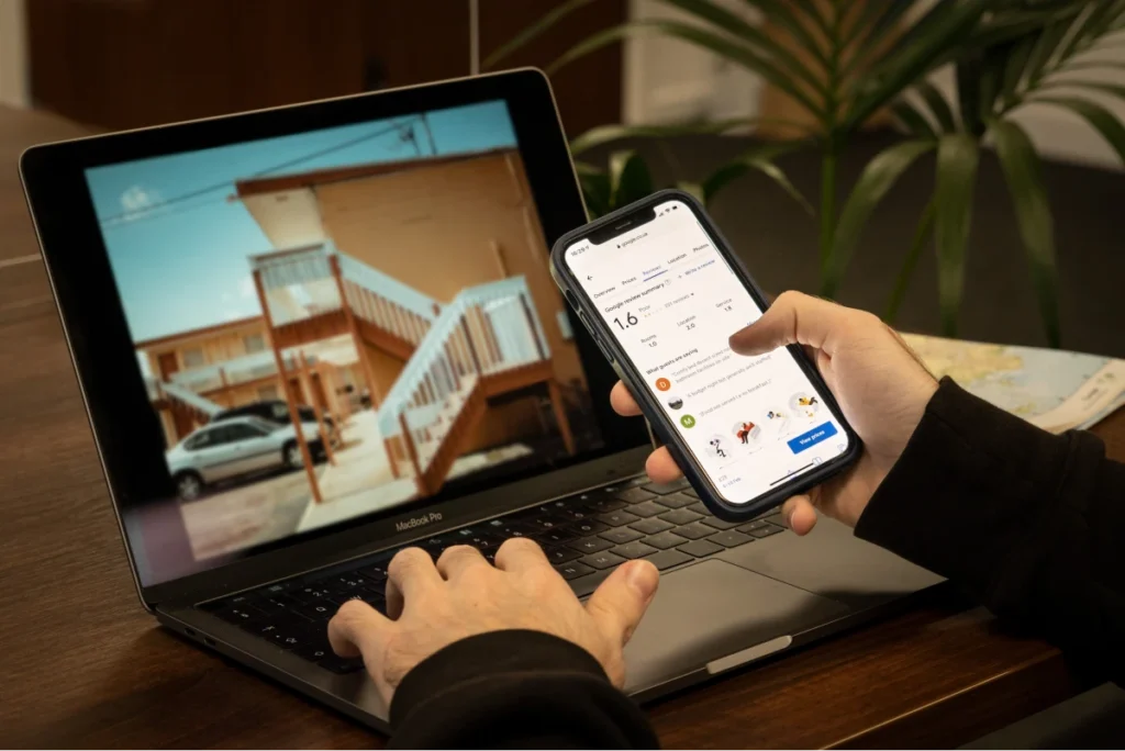 Person using smartphone and laptop with social media and property image displayed.