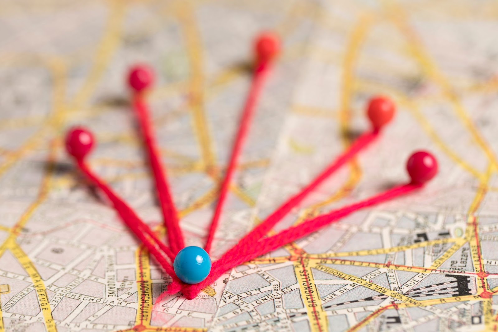 Map with colorful pins connected by red string, symbolizing travel routes or connections between locations.