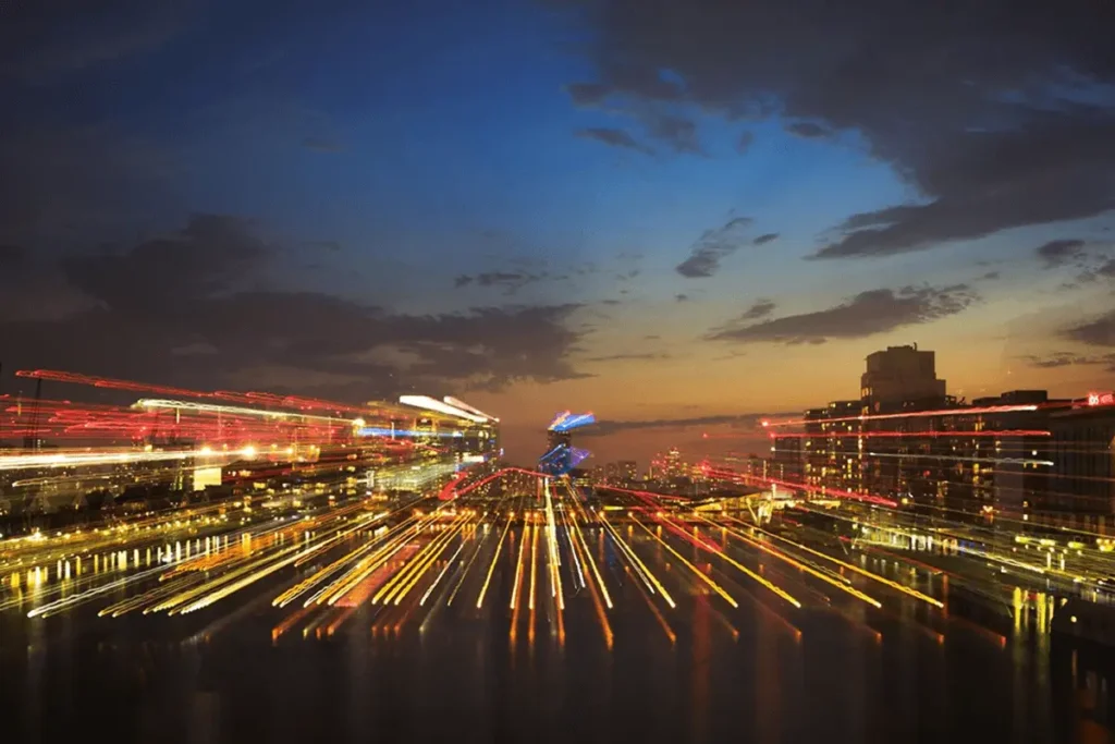 A city skyline at dusk with dynamic streaks of red and yellow lights, representing fast-paced urban development and technology.