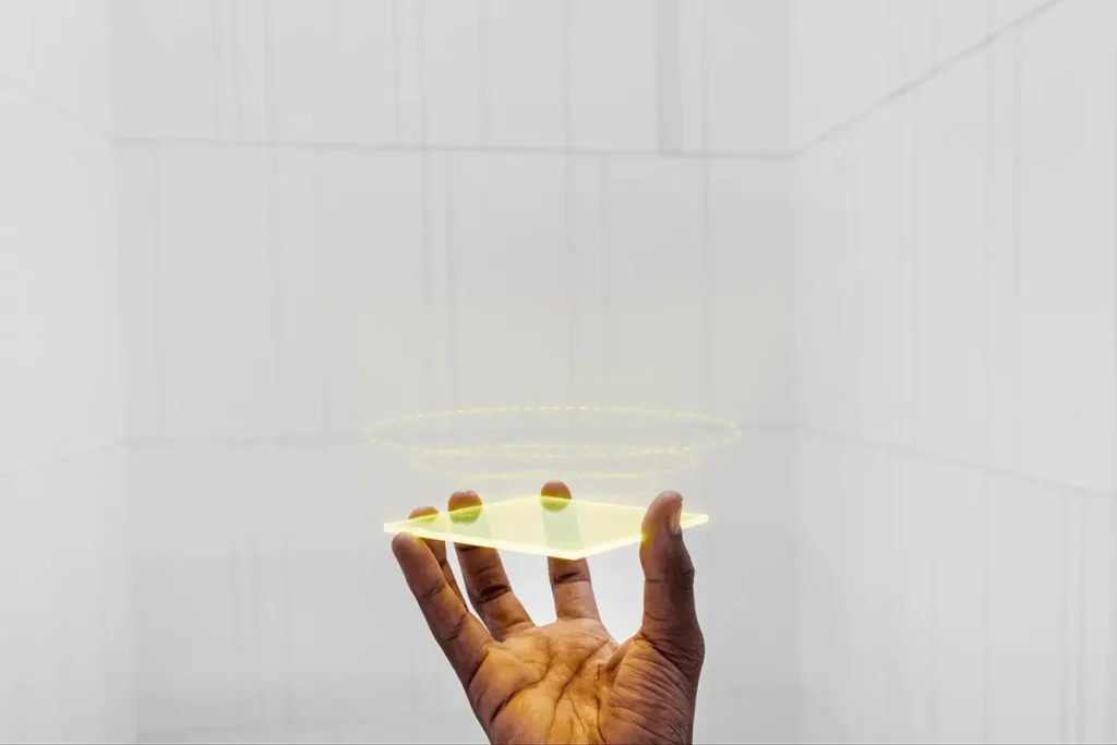 A hand holding a futuristic transparent device with a glowing holographic interface.