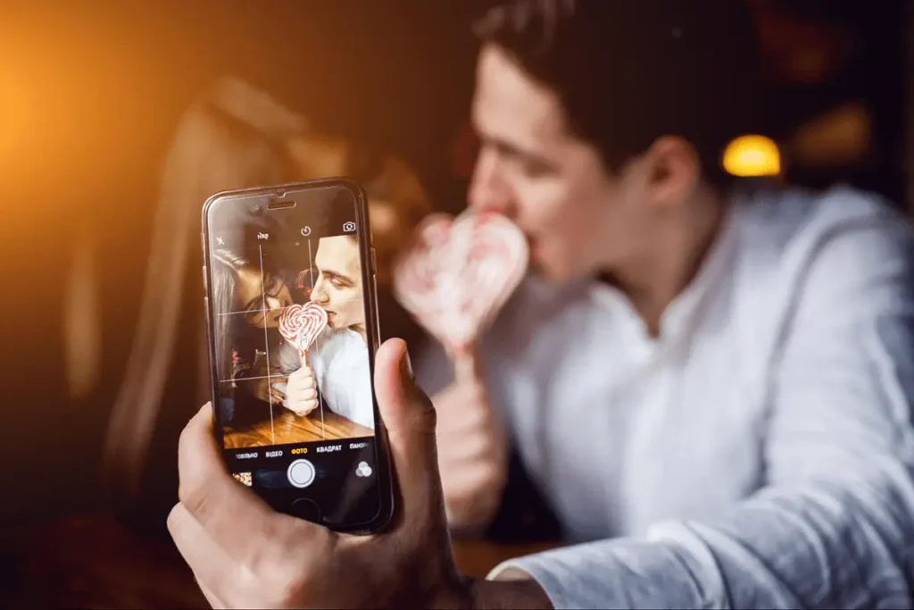 A couple taking a selfie with a smartphone, symbolizing the role of social media and technology in modern relationships.