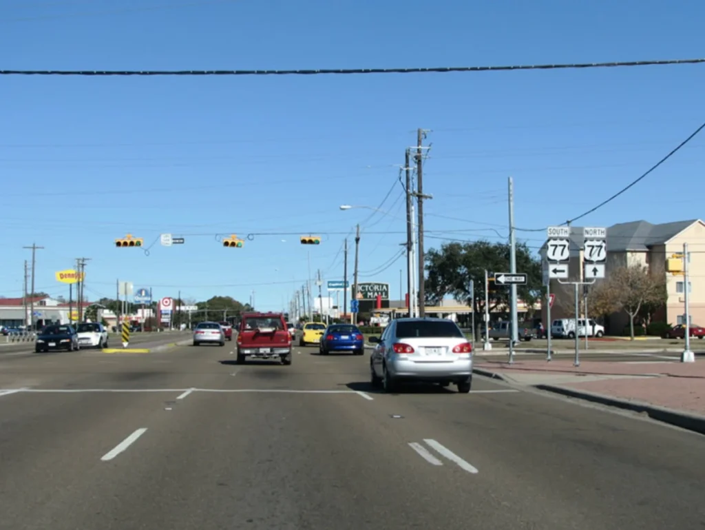A busy city intersection with street signs, traffic lights, and cars on a clear day.