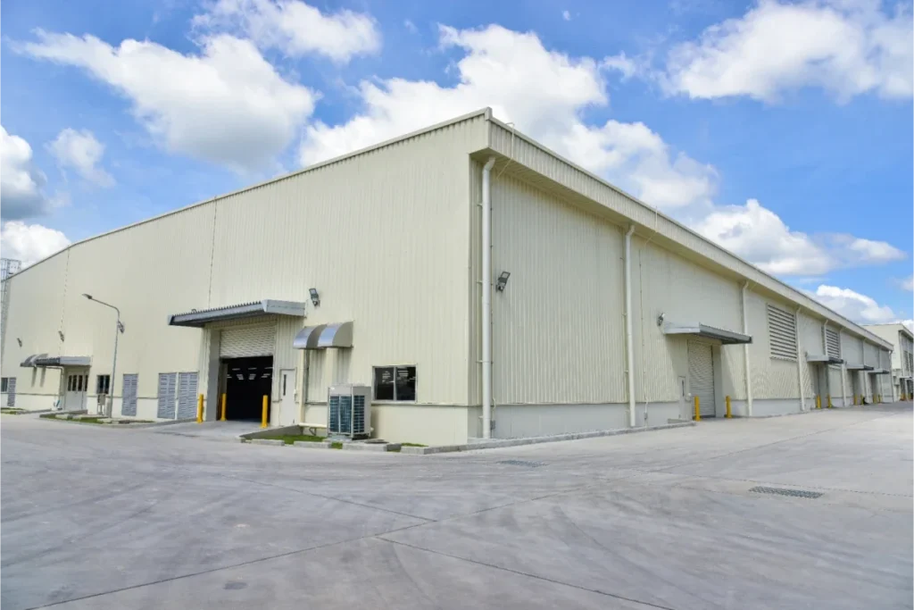 A large industrial warehouse building with clear skies and a clean concrete surface.